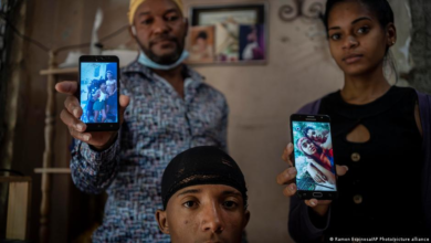 Familiares muestran fotos de Mackyanis, Emiyoslán y Yosney Emilio Román Rodriguez, que siguen presos sancionados por el delito de sedición por participar en las protestas en el barrio de La Guinera de La Habana el 12 de julio de 2021. (Ramón Espinosa / AP)